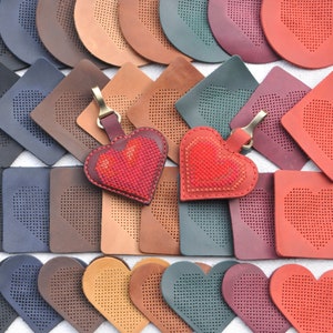 Puede incluir: Surtido de llaveros y posavasos de cuero en forma de corazón en varios colores, incluidos rojo, marrón, azul y verde. Cada pieza presenta un diseño de corazón cosido.