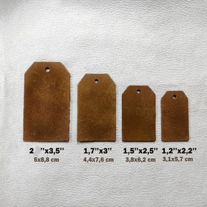 Könnte beinhalten: Vier braune Lederanhänger in verschiedenen Größen. Der größte Anhänger ist 5x8,8 cm (2" x 3,5"), gefolgt von 4,4x7,6 cm (1,7" x 3"), 3,8x6,2 cm (1,5" x 2,5") und 3,1x5,7 cm (1,2" x 2,2"). Jeder Anhänger hat ein Loch.
