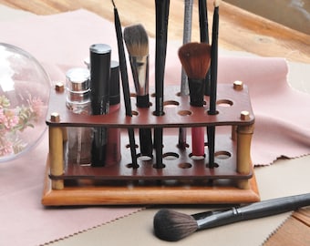 May include: A brown leather makeup brush holder with a wooden base and brass accents. The holder has multiple slots for brushes and bottles. It is filled with various makeup brushes and bottles.