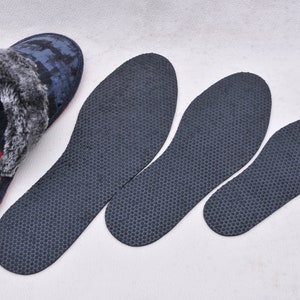 May include: Three pairs of black insoles with a honeycomb pattern, and a pair of blue and gray fuzzy slippers with a red lining.