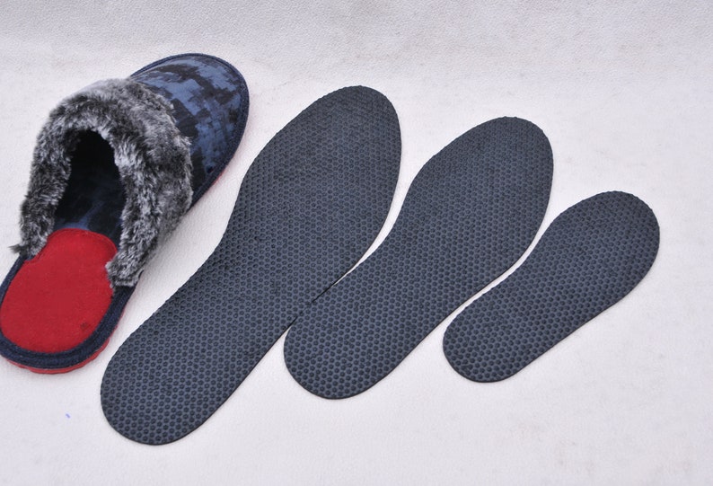 May include: Three pairs of black insoles with a honeycomb pattern, and a pair of blue and gray fuzzy slippers with a red lining.
