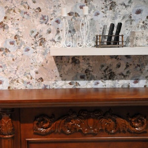 May include: A dark wood mantel with ornate carvings and a white shelf above. The shelf has two candle holders, a birdcage, and a remote control holder.