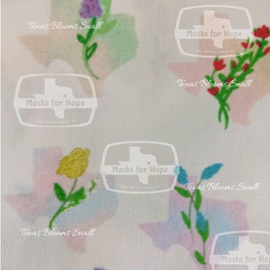 May include: A white fabric with a repeating pattern of stylized Texas outlines. Each outline is filled with a watercolor-like design in shades of pink, blue, and green. The outlines are decorated with small floral designs in various colors, including red, yellow, blue, and purple. The text "Masks for Hope" appears in a circle with a heart inside, repeated throughout the fabric.