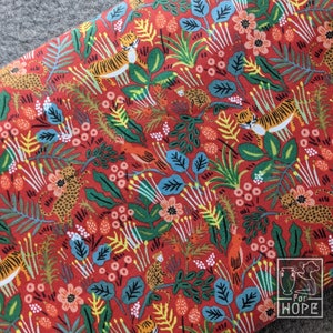 K&ouml;nnte beinhalten: Roter Stoff mit einem sich wiederholenden Muster aus Tigern, Blumen und Bl&auml;ttern. Der Stoff hat einen wei&szlig;en Hintergrund mit einem roten, gr&uuml;nen und gelben Muster. Der Stoff ist mit den Worten "For Hope" bedruckt.