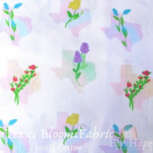 May include: White fabric with a repeating pattern of colorful flower bouquets inside the outline of the state of Texas. The fabric has the text "Texas Blooms Fabric For Hope Waco Texas 100% Cotton" printed at the bottom.