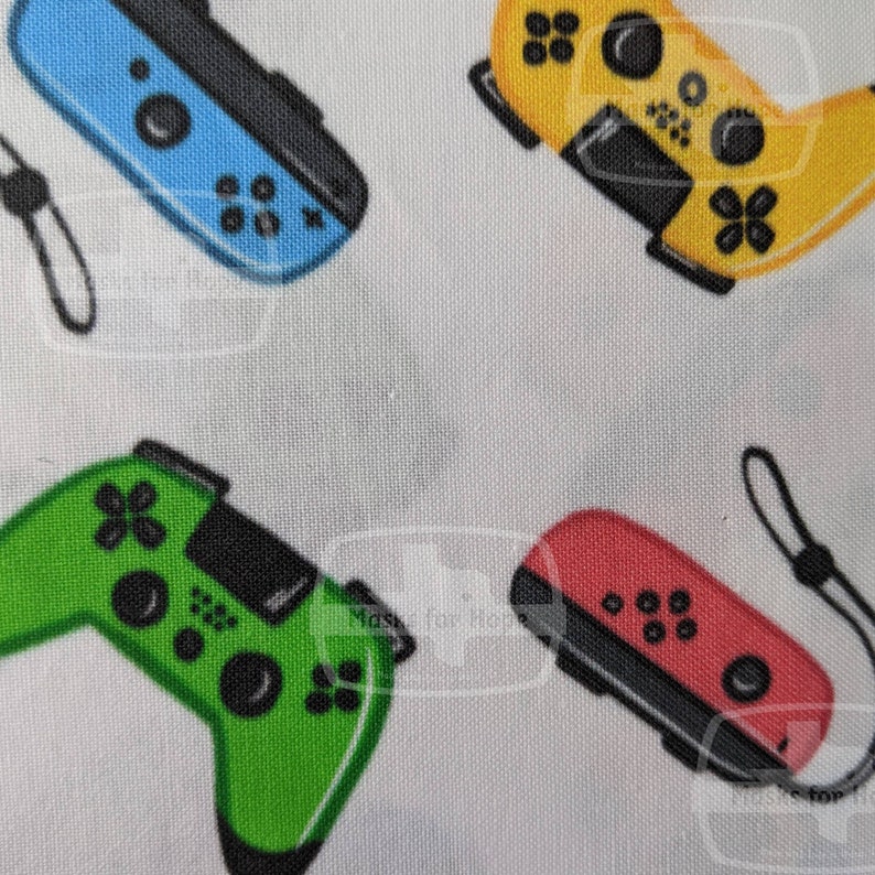 May include: A white fabric with a repeating pattern of four different colored video game controllers. The controllers are green, blue, yellow, and red.