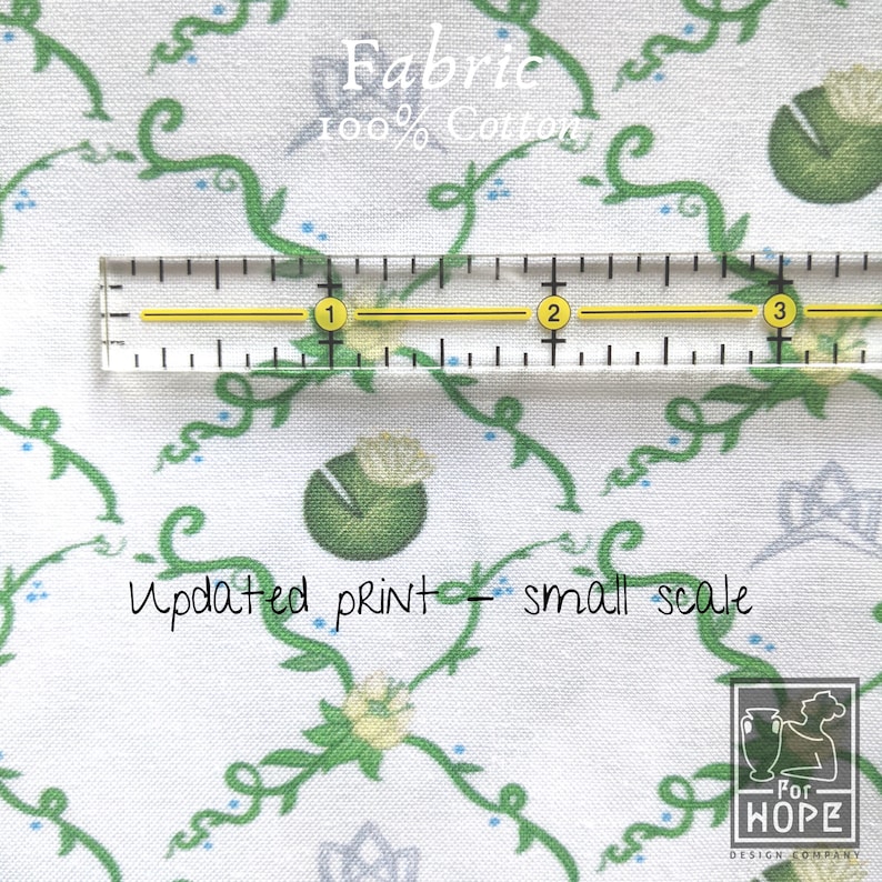 Peut inclure: Tissu en coton blanc avec un motif de vignes et de fleurs vertes. Le tissu est 100% coton et a un imprim&eacute; &agrave; petite &eacute;chelle. Une r&egrave;gle est plac&eacute;e sur le tissu pour montrer l'&eacute;chelle de l'impression. Le texte "Fabric 100% Cotton" et "Updated print - small scale" est visible sur le tissu.