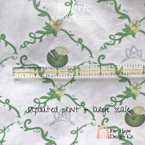Peut inclure: Tissu en coton blanc avec un motif r&eacute;p&eacute;t&eacute; de vignes vertes, de points bleus et de fleurs blanches avec des feuilles vertes. Le tissu est &eacute;tiquet&eacute; "Fabric 100% Cotton" et "Updated print - large scale".