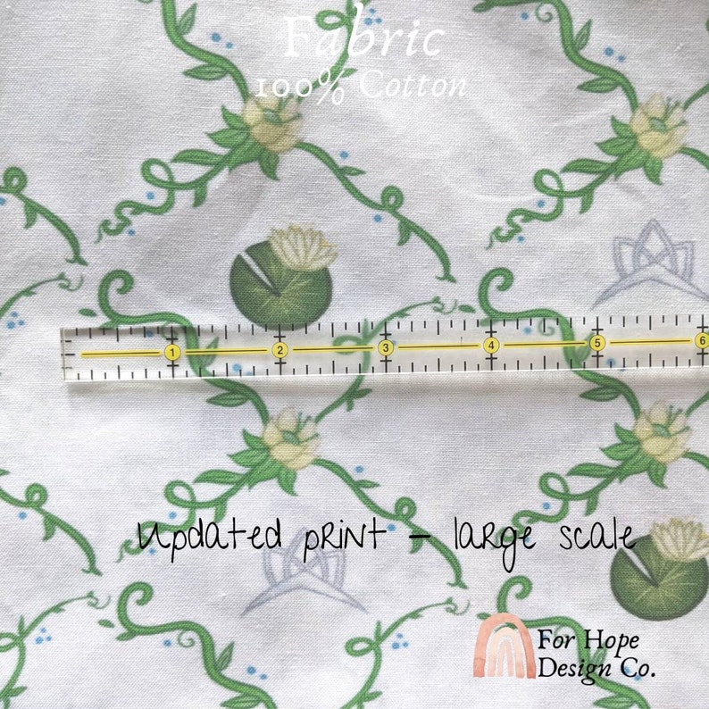 Peut inclure: Tissu en coton blanc avec un motif r&eacute;p&eacute;t&eacute; de vignes vertes, de points bleus et de fleurs blanches avec des feuilles vertes. Le tissu est &eacute;tiquet&eacute; "Fabric 100% Cotton" et "Updated print - large scale".