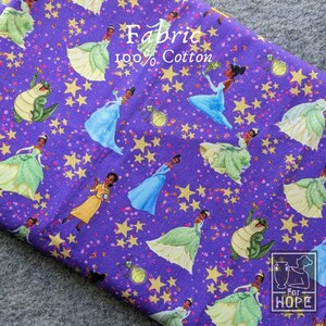 May include: Purple cotton fabric with a repeating pattern of a princess in various gowns, stars, and a frog. The fabric has the words "Fabric" and "100% Cotton" printed on it.