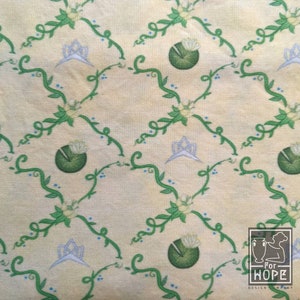Peut inclure: Un tissu de couleur cr&egrave;me avec un motif r&eacute;p&eacute;titif de vignes vertes, de fleurs bleues et de couronnes blanches. Le motif est sur un fond jaune clair.