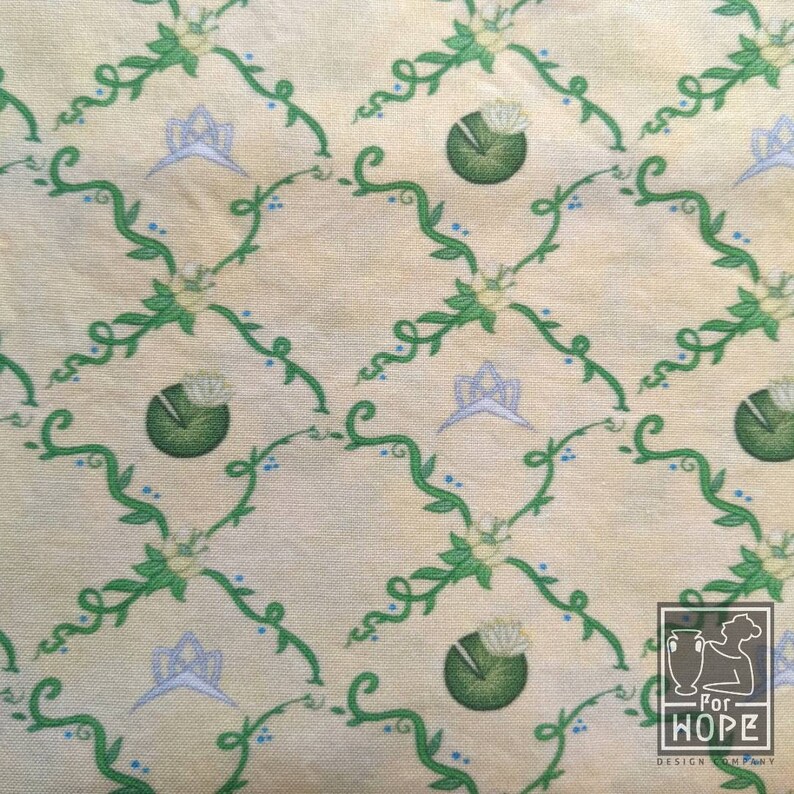 Peut inclure: Un tissu de couleur cr&egrave;me avec un motif r&eacute;p&eacute;titif de vignes vertes, de fleurs bleues et de couronnes blanches. Le motif est sur un fond jaune clair.