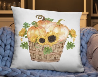 May include: A white throw pillow with a watercolor illustration of a wooden bucket filled with three pumpkins and sunflowers. The pumpkins are orange and the sunflowers are yellow with brown centers.