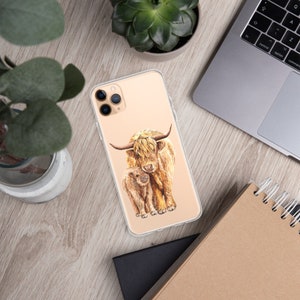 May include: A clear phone case with a watercolor illustration of a Highland cow and her calf. The cow is brown and white with long, shaggy hair. The calf is smaller and has a more reddish-brown color.