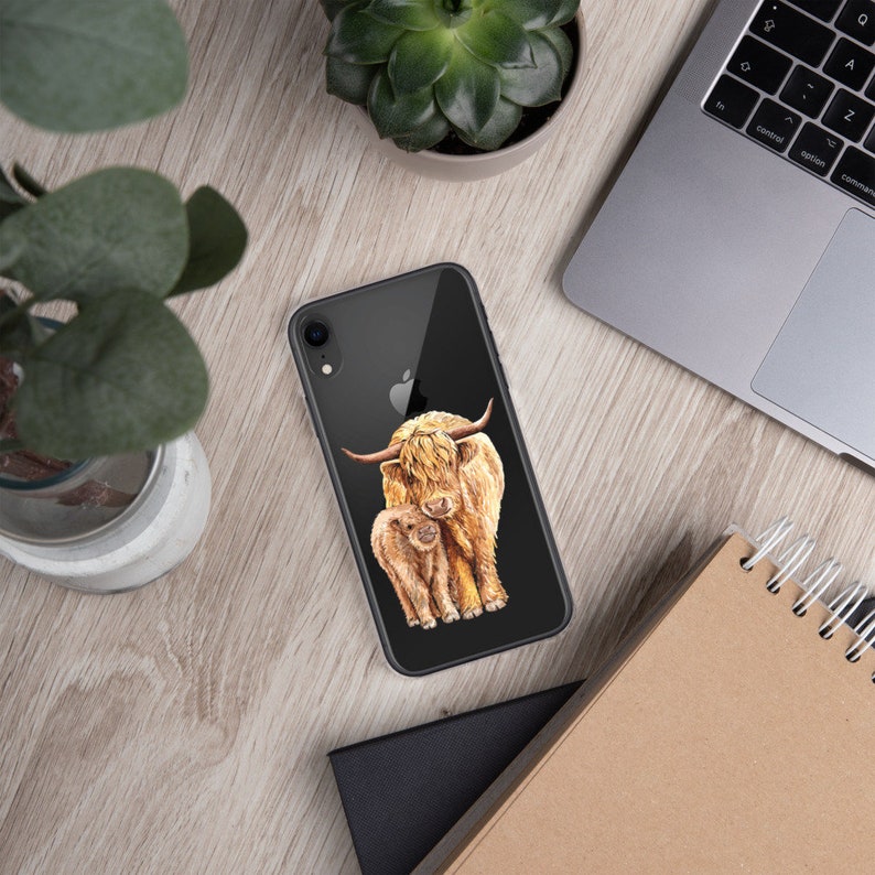 May include: A black phone case with a watercolor illustration of a Highland cow and calf. The cow is brown and white with long hair and the calf is a lighter brown.