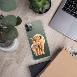May include: A clear phone case with a watercolor illustration of a Highland cow and calf. The cow is brown and white with long, shaggy hair. The calf is smaller and a lighter brown color. The background is a dark green.
