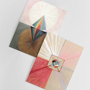 Puede incluir: Dos pinturas abstractas con formas geom&eacute;tricas y colores vibrantes. La primera pintura presenta una pir&aacute;mide de colores arco&iacute;ris con un c&iacute;rculo blanco en el fondo. La segunda pintura presenta un cuadrado con una espiral colorida en su interior, rodeada de l&iacute;neas radiantes en rosa, blanco y beige.