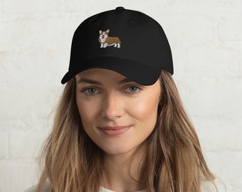 May include: A black baseball cap with an embroidered image of a brown and white corgi dog.