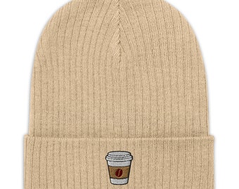 May include: A beige knitted beanie with a small embroidered design of a coffee cup with a coffee bean on the side.