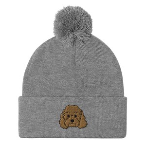 May include: Gray beanie with a brown embroidered poodle on the front and a gray pom pom on top.