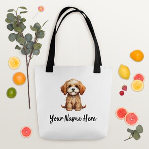 May include: White canvas tote bag with black handles. The bag features a cartoon illustration of a brown and white puppy with the text "Your Name Here" printed below the image.