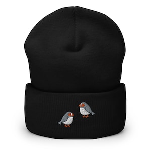 Könnte beinhalten: Schwarze Mütze mit Umschlag und zwei gestickten grauen Vögeln mit orangefarbenen Schnäbeln.