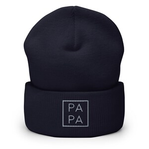 May include: A navy blue beanie with a white square patch that says "PA PA" in white text.