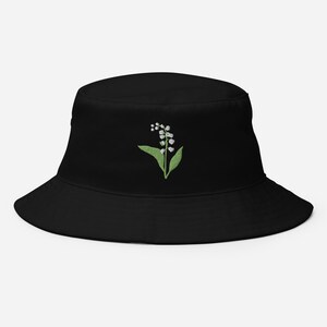 May include: Black bucket hat with an embroidered white lily of the valley flower design.