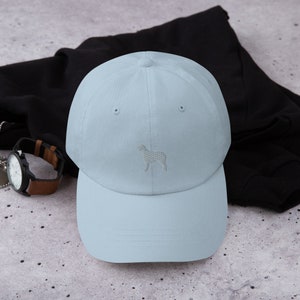 May include: A light blue baseball cap with a white embroidered silhouette of a dog on the front.