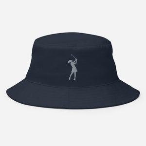 Peut inclure: Un chapeau bob bleu marine avec une silhouette brodée grise d'une femme jouant au golf.