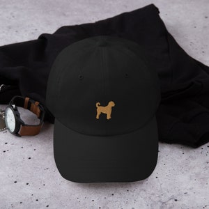 Peut inclure: Une casquette de baseball noire avec une silhouette de chien brodée en brun sur le devant.