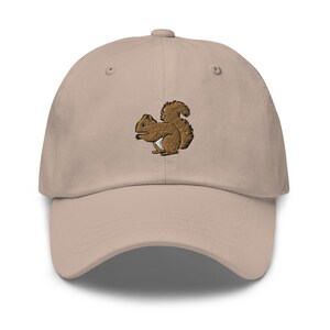 May include: A beige baseball cap with an embroidered brown squirrel design.