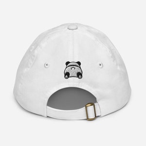 Può includere: Cappellino da baseball bianco con un design di panda bianco e nero ricamato sul retro.