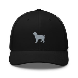 Op de afbeelding: Zwarte truckercap met een grijs geborduurd silhouet van een hond op de voorkant.