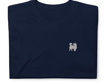 May include: A navy blue t-shirt with a small embroidered image of a white dog on the left chest.