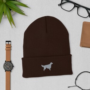 May include: A brown knit beanie with a gray embroidered silhouette of a golden retriever.