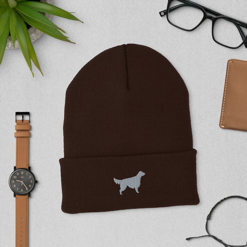 May include: A brown knit beanie with a gray embroidered silhouette of a golden retriever.