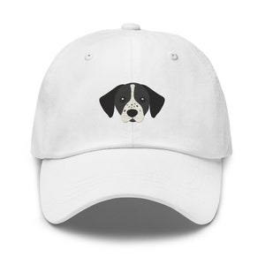 Puede incluir: Gorra de béisbol blanca con un rostro de perro negro y blanco bordado.