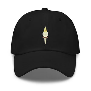 Könnte beinhalten: Eine schwarze Baseballkappe mit einem gestickten Bild eines gelben und weißen Nymphensittichs.