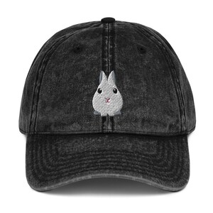 Puede incluir: Una gorra de béisbol de mezclilla vintage negra lavada con un conejo gris bordado en la parte delantera.