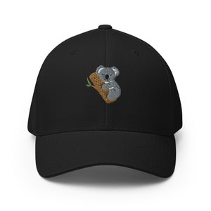 May include: A black baseball cap featuring an embroidered image of a koala bear sleeping on a tree branch.