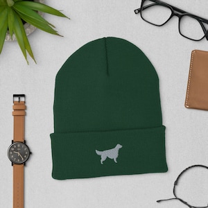 May include: A dark green beanie with a white embroidered silhouette of a golden retriever.