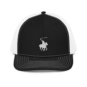 Puede incluir: Una gorra de camionero negra y blanca con un logotipo de jugador de polo bordado en blanco en la parte delantera. La gorra tiene una parte trasera de malla negra y una visera negra.