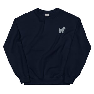 Op de afbeelding: Een donkerblauwe trui met een grijs geborduurd silhouet van een kleine hond op de voorkant.