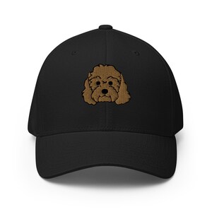 May include: A black baseball cap with an embroidered brown poodle face.