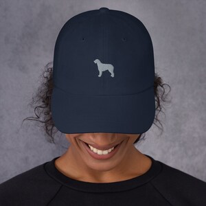 May include: A navy blue baseball cap with a light gray embroidered silhouette of a dog on the front.