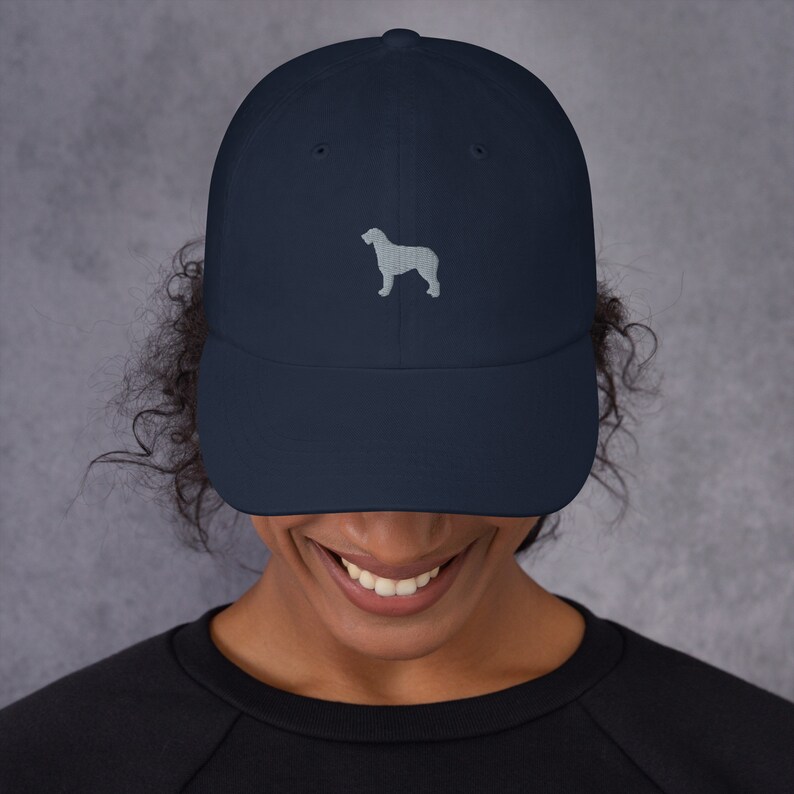 May include: A navy blue baseball cap with a light gray embroidered silhouette of a dog on the front.