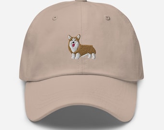 May include: A beige baseball cap with an embroidered image of a brown and white corgi dog with its tongue sticking out.