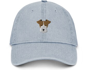 May include: A light blue denim baseball cap with an embroidered image of a wirehaired fox terrier.