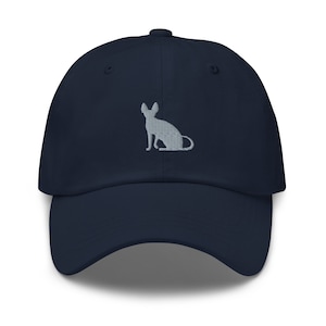 Puede incluir: Una gorra de béisbol azul marino con una silueta de gato bordada en gris.